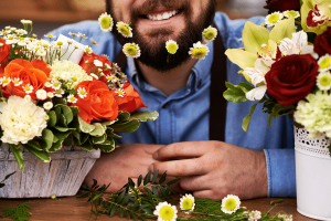 Empresário Danilo Jordão Teixeira sorrindo com dois vasos de flores