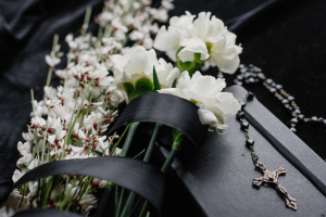 Flores Brancas e Um colar de terço em cima de um caixão